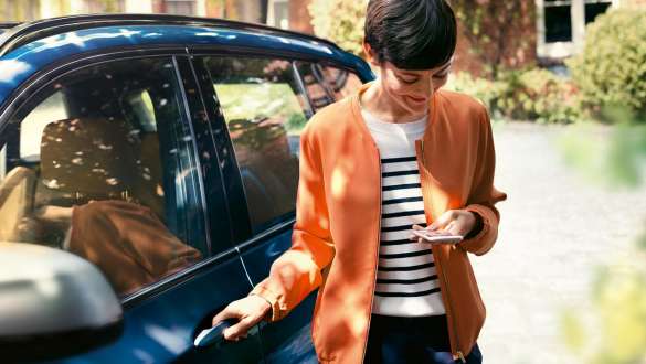 BMW Teleservices BMW Teleservices vrouw met smartphone naast BMW deur