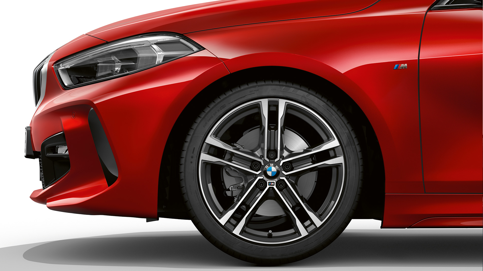 BMW 1 Serie model M Sport, front van opzij. BMW 1 Serie model M Sport in Melbourne Rot metallic, front van opzij met 17 inch lichtmetalen M wielen in dubbelspaaksdesign 550 M Bicolor.