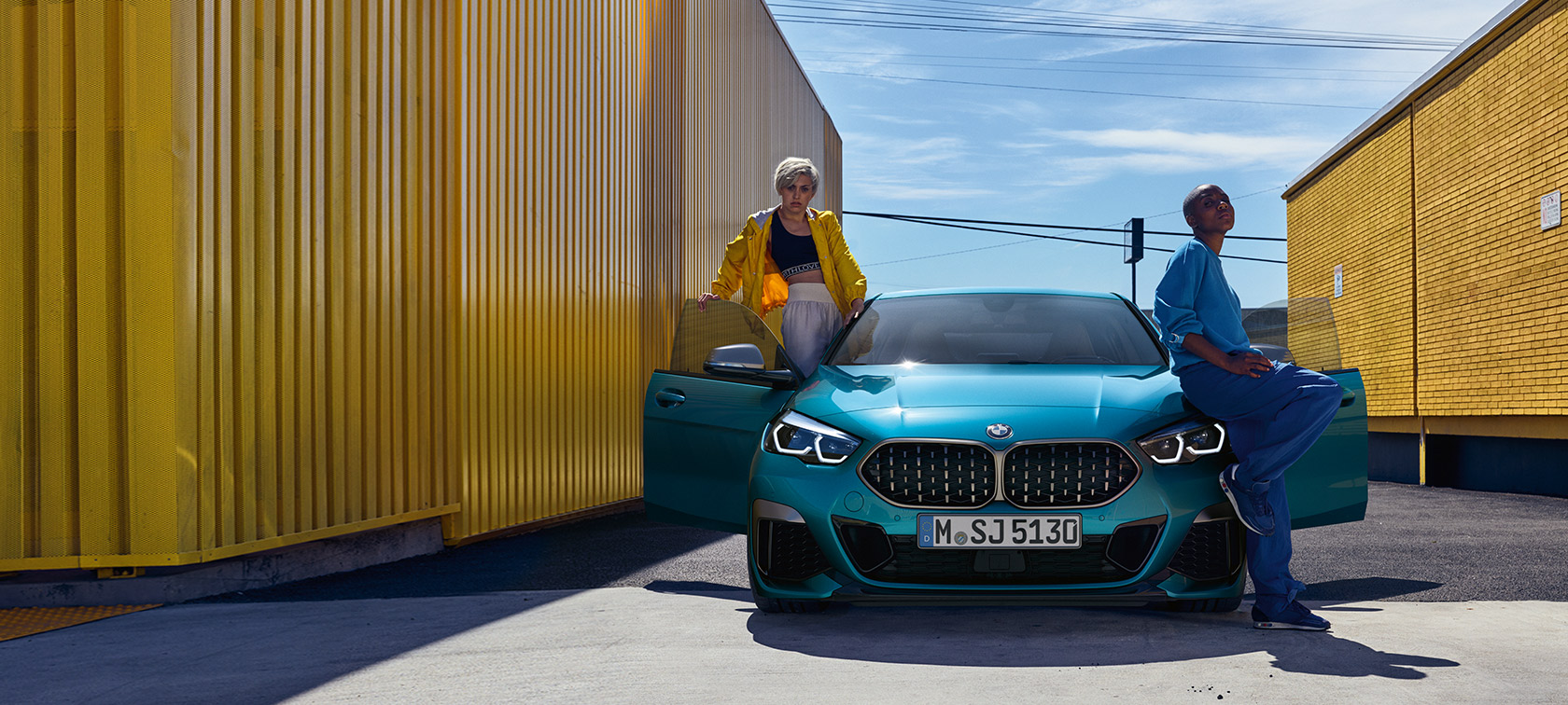 BMW 2 Serie Gran Coupé F44 vooraanzicht BMW 2 Serie Gran Coupé F44 Snapper Rocks Blau metallic, vooraanzicht met geopende portieren en twee personen
