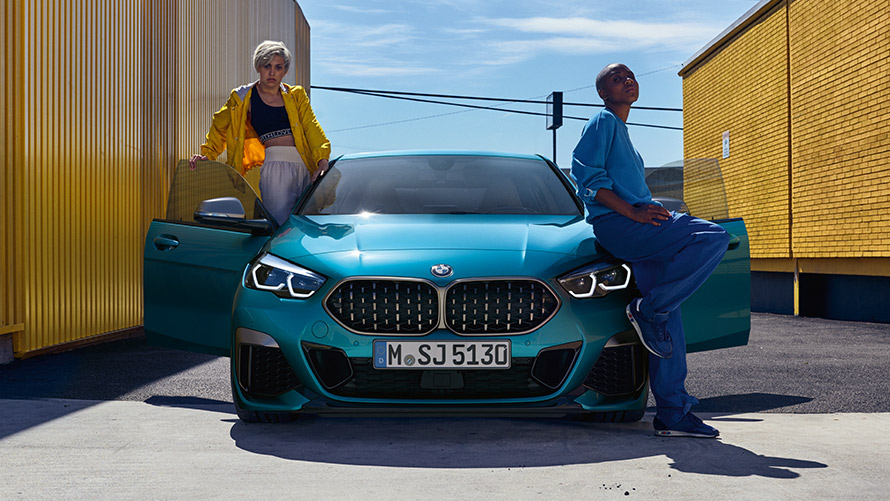 BMW 2 Serie Gran Coupé F44 vooraanzicht BMW 2 Serie Gran Coupé F44 Snapper Rocks Blau metallic, vooraanzicht met geopende portieren en twee personen
