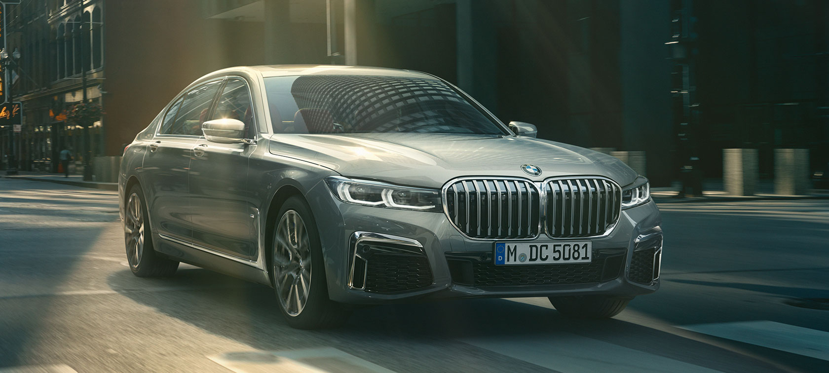 Rijdende grijze BMW 7 Serie Sedan, driekwart vooraanzicht Driekwart vooraanzicht van grijze BMW 7 Serie Sedan die rijdt door stedelijke omgeving
