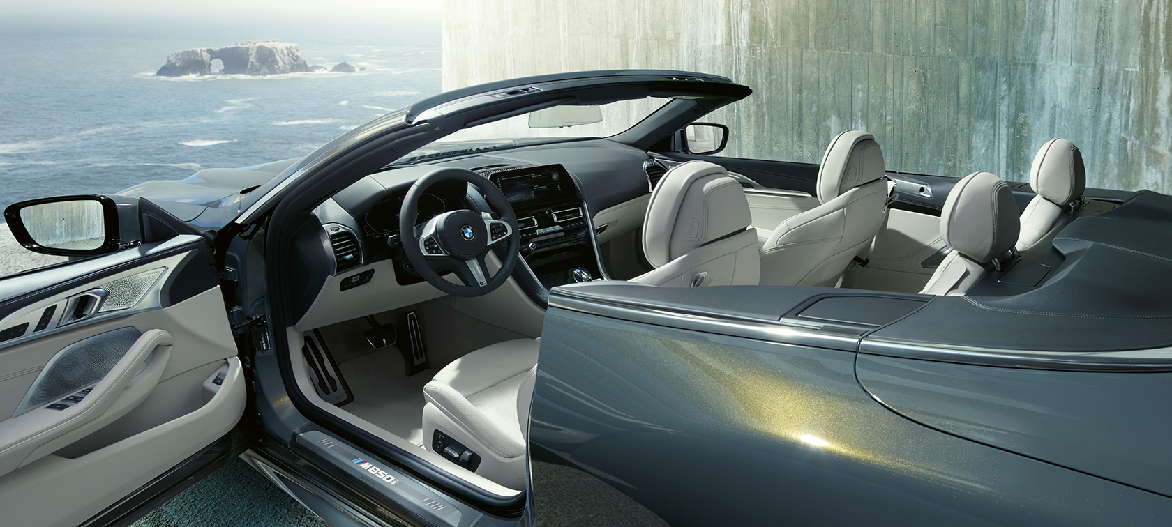 BMW M850i xDrive in Dravitgrau metallic, zijaanzicht, cabriokap en portier geopend. BMW M850i xDrive in Dravitgrau metallic, zijaanzicht, cabriokap en portier geopend.