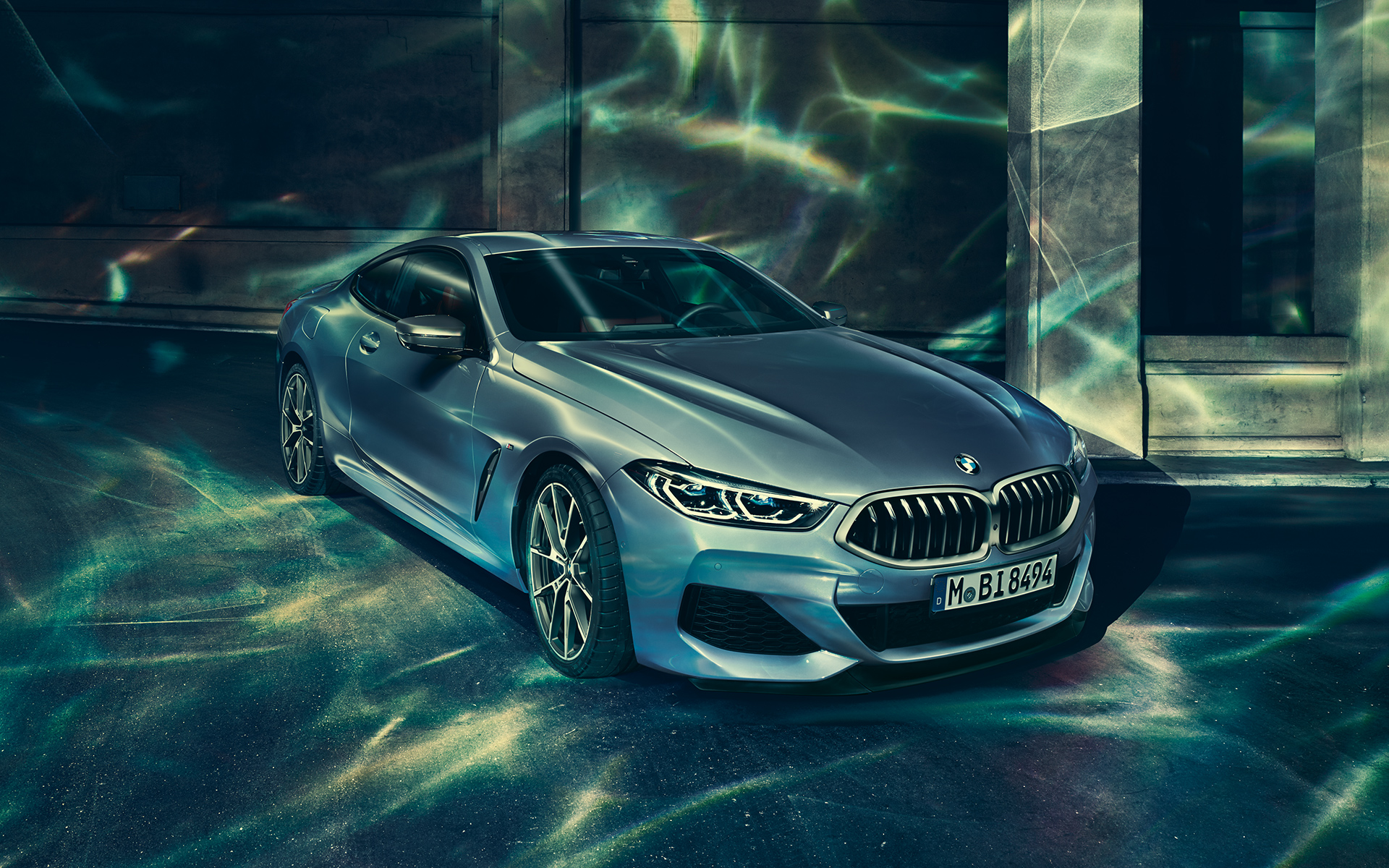 BMW 8 Serie Coupé, driekwart linker vooraanzicht Driekwart rechter achteraanzicht van een stilstaande BMW 8 Serie Coupé met op de achtergrond een stedelijke skyline.
