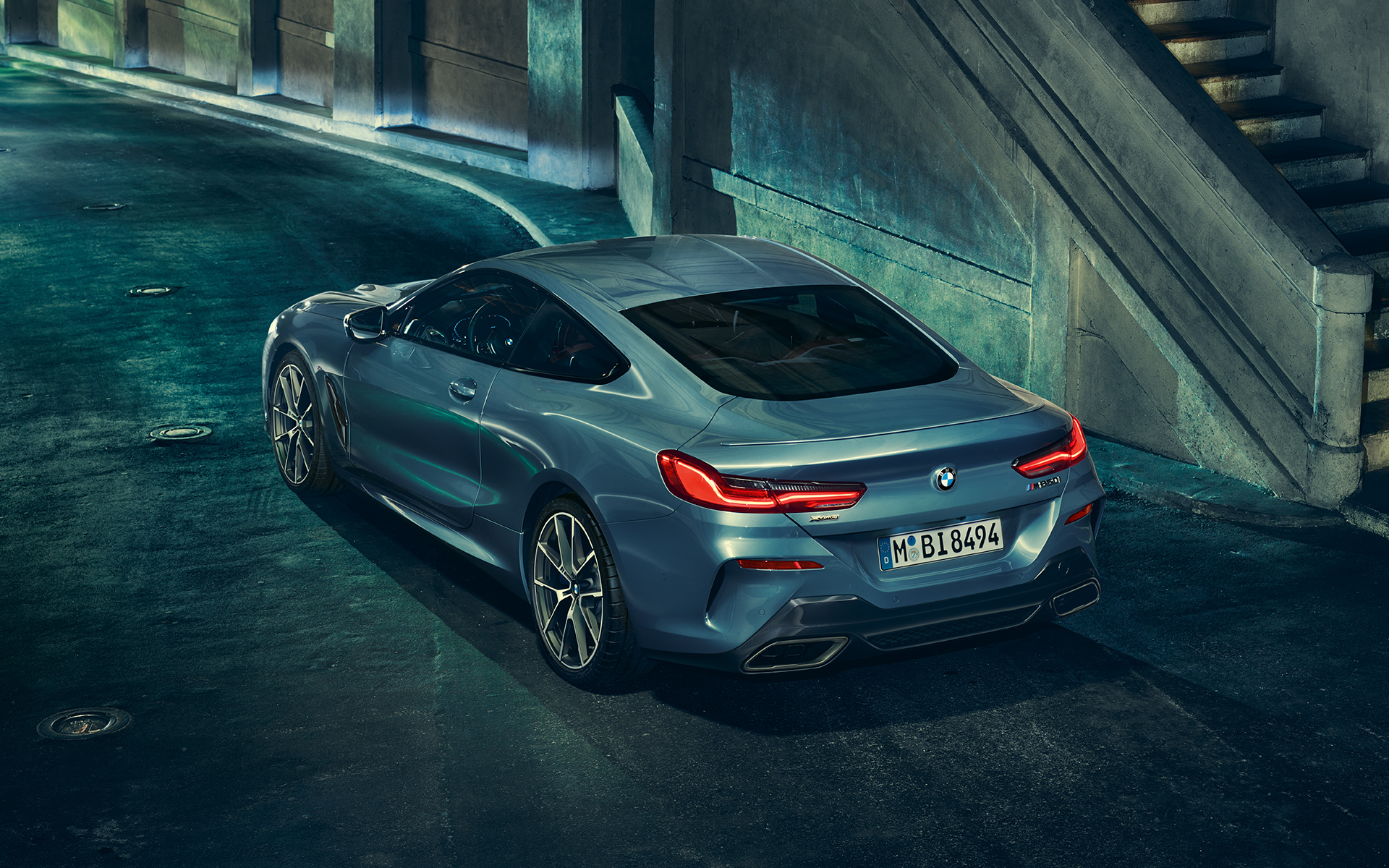 BMW 8 Serie Coupé, driekwart achteraanzicht Driekwart linker achteraanzicht van een stilstaande BMW 8 Serie Coupé met op de achtergrond een stedelijke skyline.