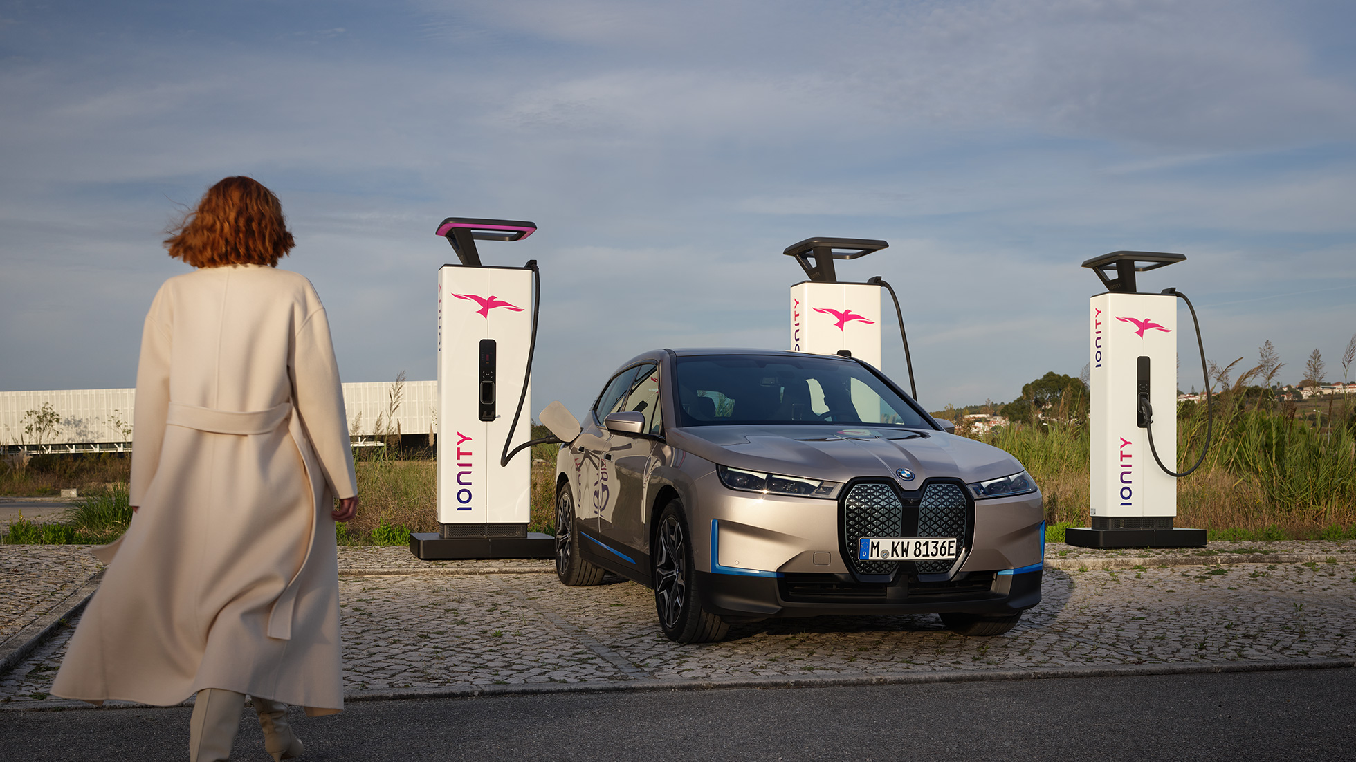 BMW iX driekwart vooraanzicht bij laadstation BMW iX Kaschmirsilber i20 driekwart vooraanzicht bij laadstation