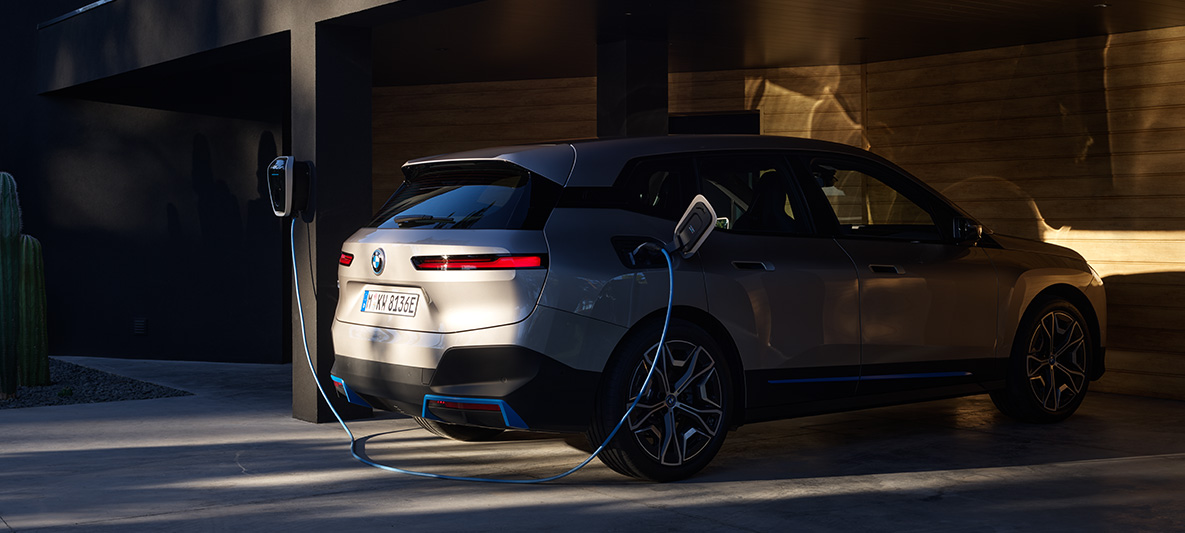 BMW iX driekwart achteraanzicht opladen aan BMW Wallbox BMW iX Kaschmirsilber i20 driekwart achteraanzicht opladen aan BMW Wallbox