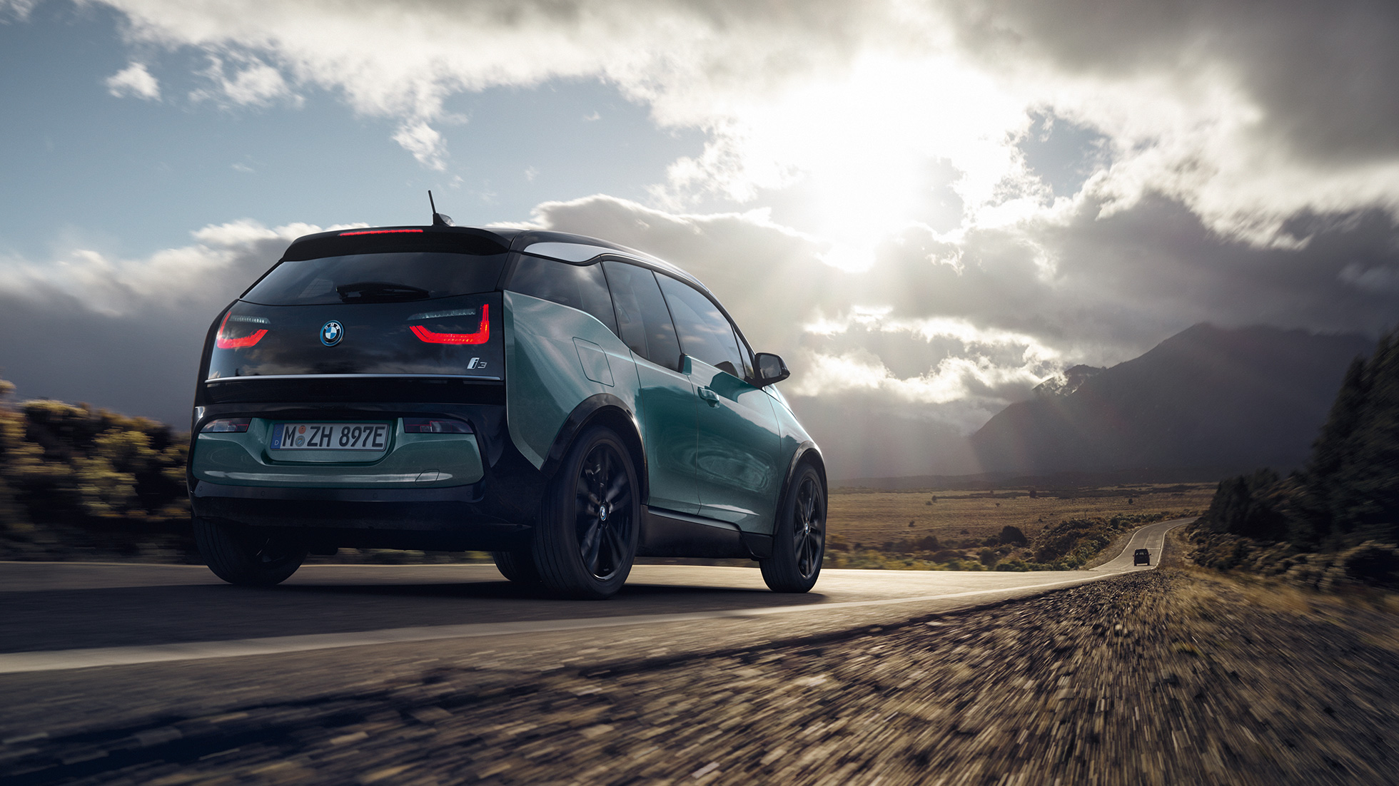 BMW i3 driekwart achteraanzicht op buitenweg BMW i3 Jucarobeige met accenten in Frozen Grey metallic driekwart achteraanzicht op buitenweg
