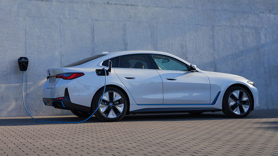 BMW i4 eDrive40 G26 zijaanzicht met BMW Wallbox BMW i4 eDrive40 G26 Mineralweiß zijaanzicht bij muur met BMW Wallbox