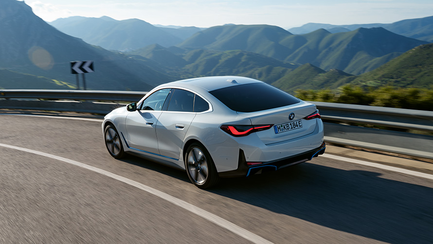 BMW i4 eDrive40 G26 driekwart achteraanzicht rijdend BMW i4 eDrive40 G26 Mineralweiß driekwart vooraanzicht rijdend