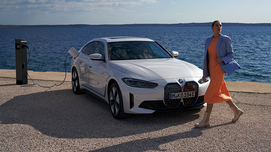 BMW i4 eDrive40 G26 2021 driekwart vooraanzicht bij laadstation BMW i4 eDrive40 G26 2021 Mineralweiß driekwart vooraanzicht aan laadpaal