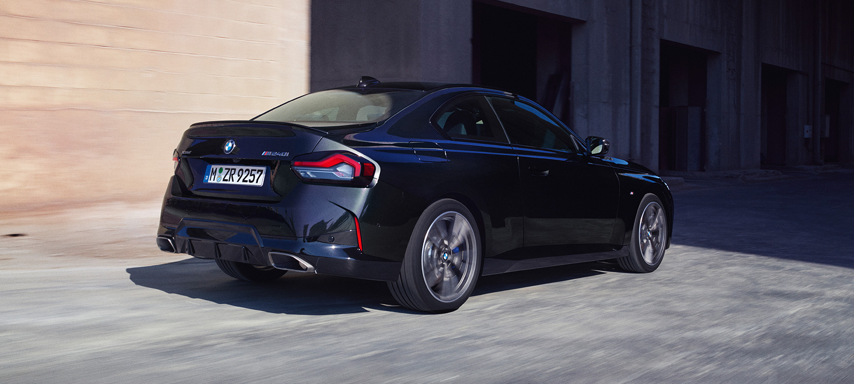 Driekwart achteraanzicht BMW M240i xDrive Coupé G42 BMW M240i xDrive Coupé G42 Saphirschwarz metallic driekwart achteraanzicht rijdend