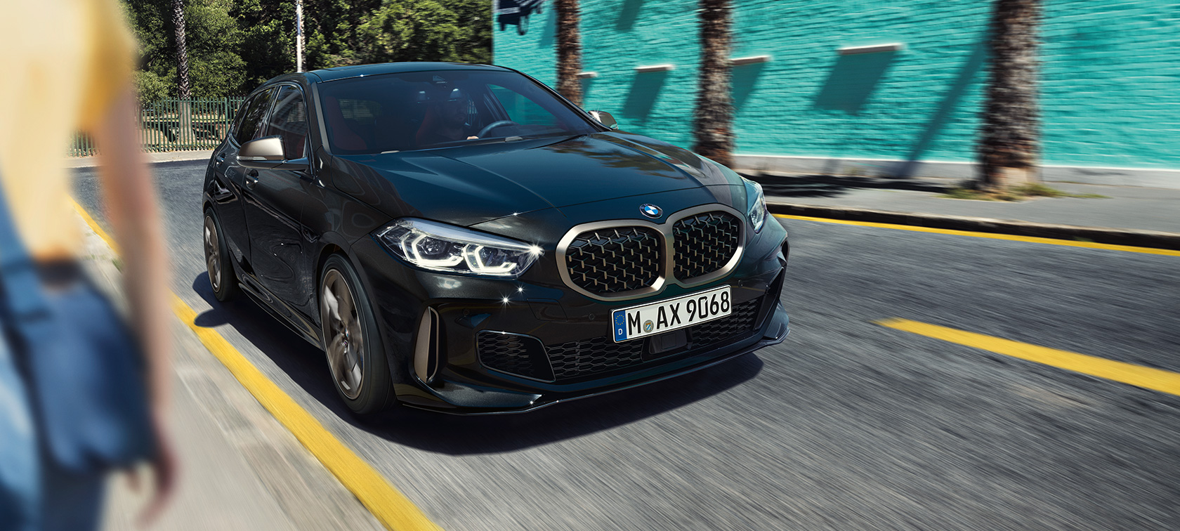 BMW M135i xDrive, driekwart vooraanzicht. BMW M135i xDrive in Saphirschwarz metallic driekwart vooraanzicht rijdend.