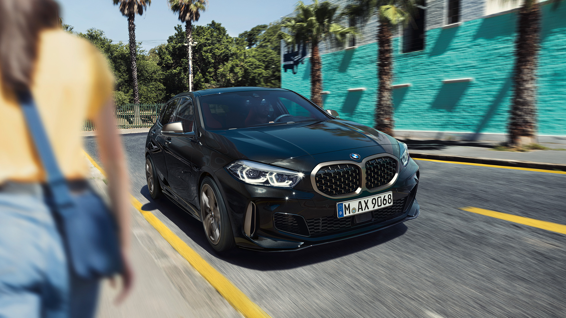 BMW M135i xDrive, driekwart vooraanzicht rijdend. BMW M135i xDrive in Saphirschwarz metallic, driekwart vooraanzicht rijdend.
