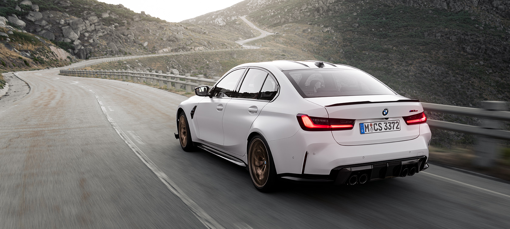 BMW M3 CS G80 driekwart achteraanzicht rijdend BMW M3 CS G80 driekwart achteraanzicht rijdend in berglandschap