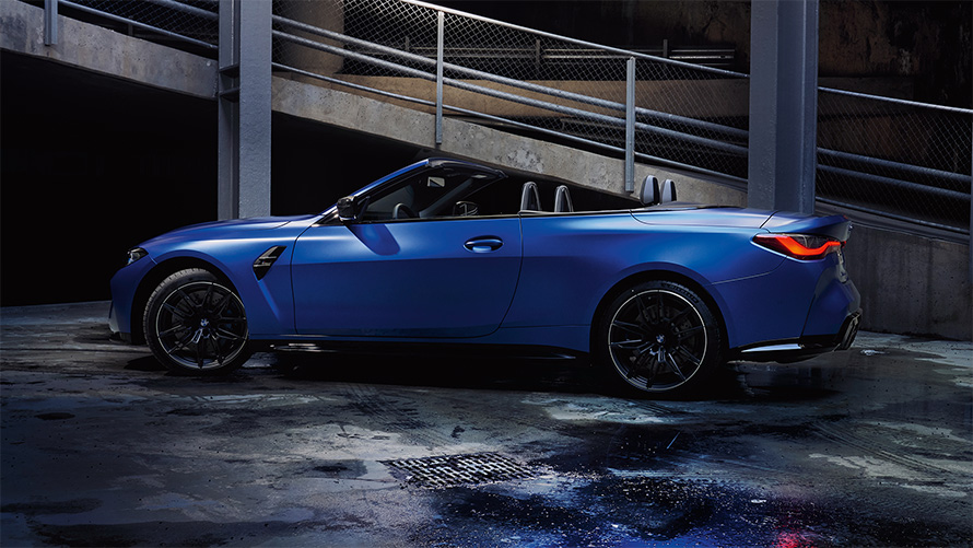 BMW M4 Competition Cabrio met M xDrive G83 zijaanzicht met open kap BMW M4 Competition Cabrio met M xDrive G83 Frozen Portimao Blau metallic zijaanzicht met open cabriokap