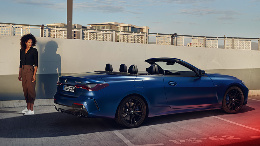 BMW Financial Services voor de BMW 4 Serie Cabrio Vrouw staat achter BMW 4 Serie cabrio op parkeerniveau BMW Financial Services