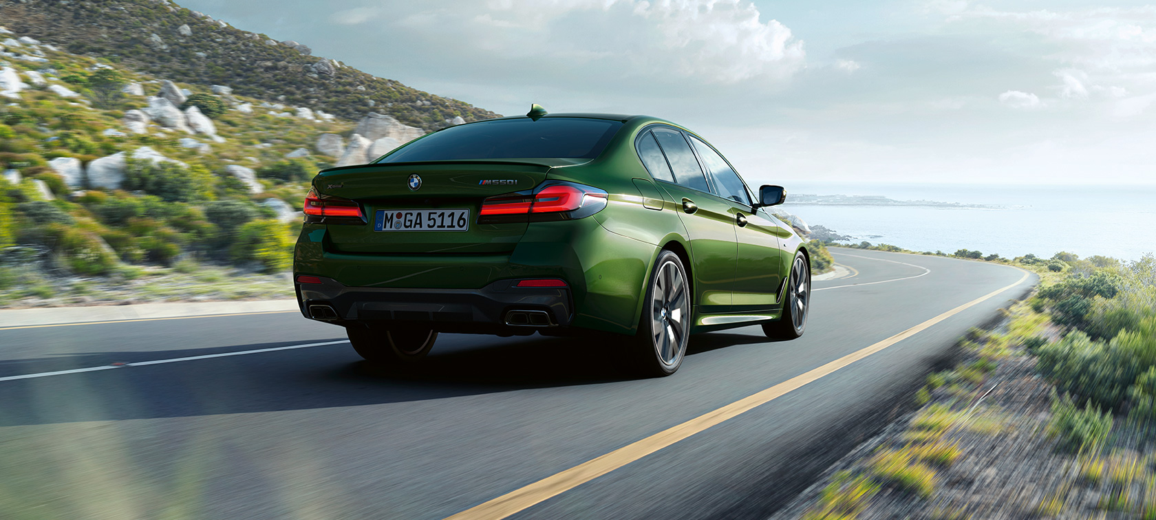 BMW M550i xDrive Sedan G30 LCI driekwart achteraanzicht rijdend BMW M550i xDrive Sedan G30 LCI BMW Individual Verde Ermes metallic driekwart achteraanzicht rijdend