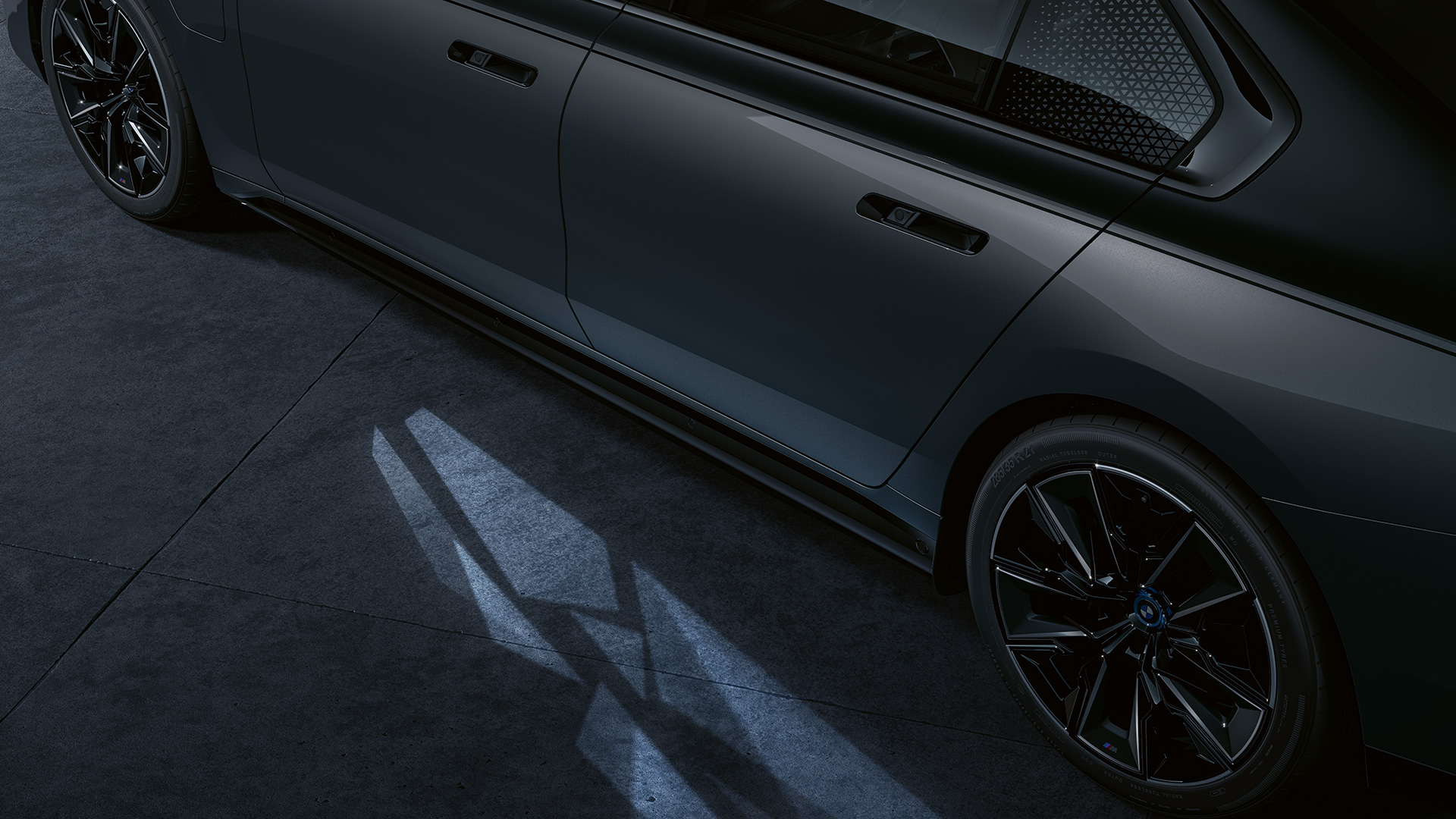 Verlichtingsconcept BMW M760e xDrive Sedan G70 two-tone carrosseriekleur Saphirschwarz metallic BMW Individual Dravitgrau metallic close-up van opzij met ingeschakelde Welcome Light Carpet