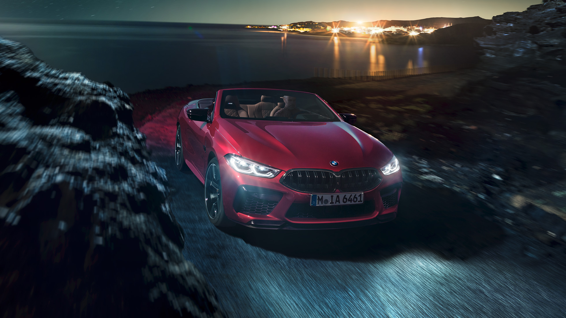 BMW M8 Competition Cabrio, driekwart voorzijde. BMW M8 Competition Cabrio in Motegi Rot metallic, geopende softtop, driekwart voorzijde, rijdend.