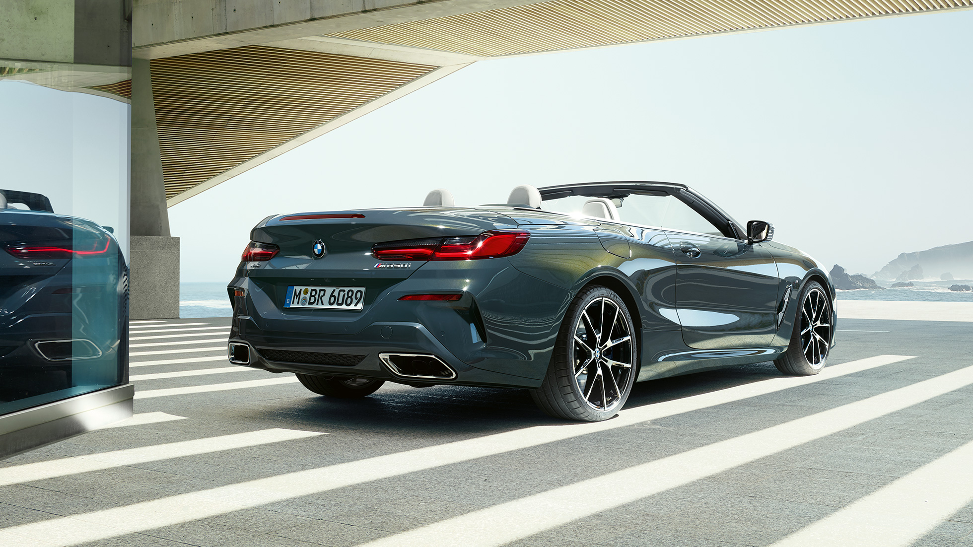 BMW M850i xDrive Cabrio, driekwart achteraanzicht. BMW M850i xDrive Cabrio in Dravitgrau metallic met open softtop, driekwart achteraanzicht, geparkeerd.