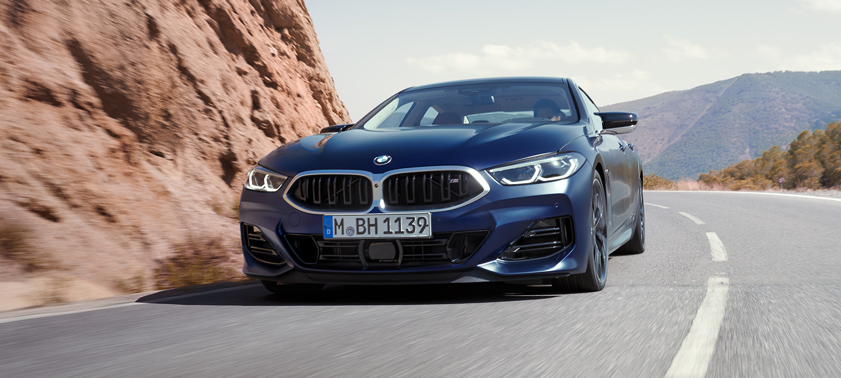 Driekwart vooraanzicht rijdend BMW M850i xDrive Gran Coupé F93 LCI facelift BMW M850i xDrive Gran Coupé F93 LCI facelift BMW Individual Frozen Tansanitblau metallic driekwart vooraanzicht rijdend in bocht