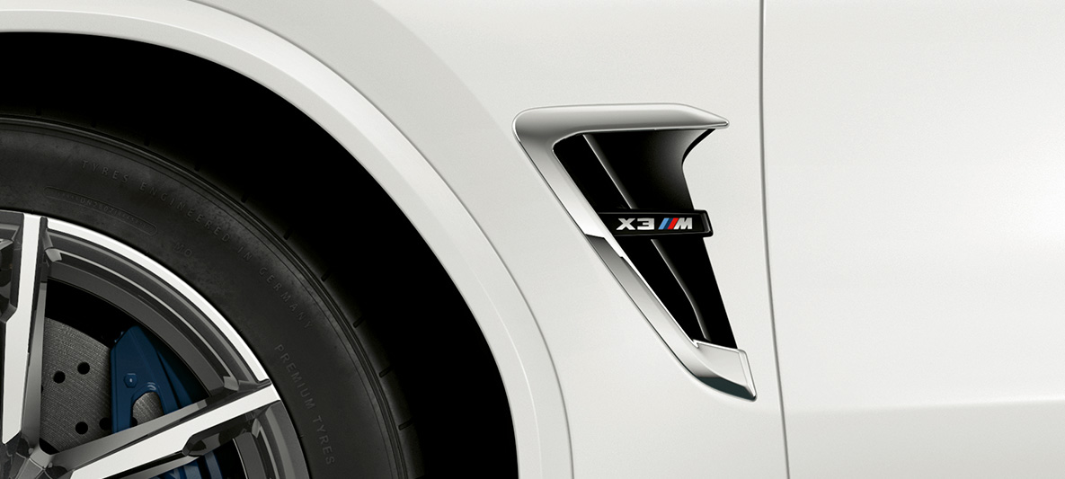 BMW X3 M, M airbreathers. BMW X3 M in Alpinweiß, exterieur, M airbreathers met chroomhighlights en modelaanduiding.