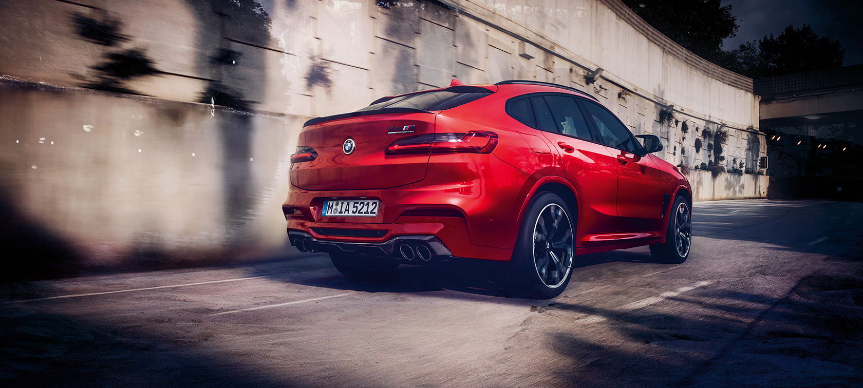 BMW X4 M Competition, driekwart achteraanzicht. BMW X4 M Competition in Toronto Rot metallic, rijdend, exterieur, driekwart achteraanzicht.