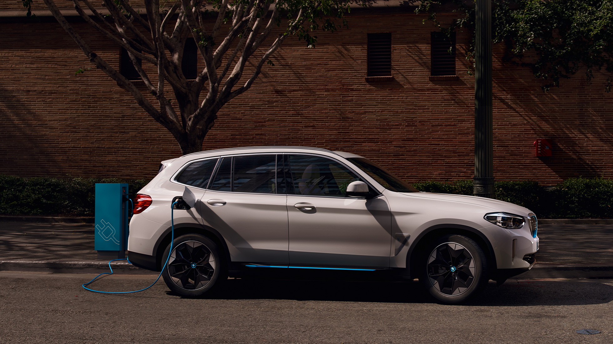 Snelladen BMW iX3 G08 zijaanzicht bij openbaar laadstation Snelladen BMW iX3 G08 Mineralweiß metallic zijaanzicht bij openbaar laadstation