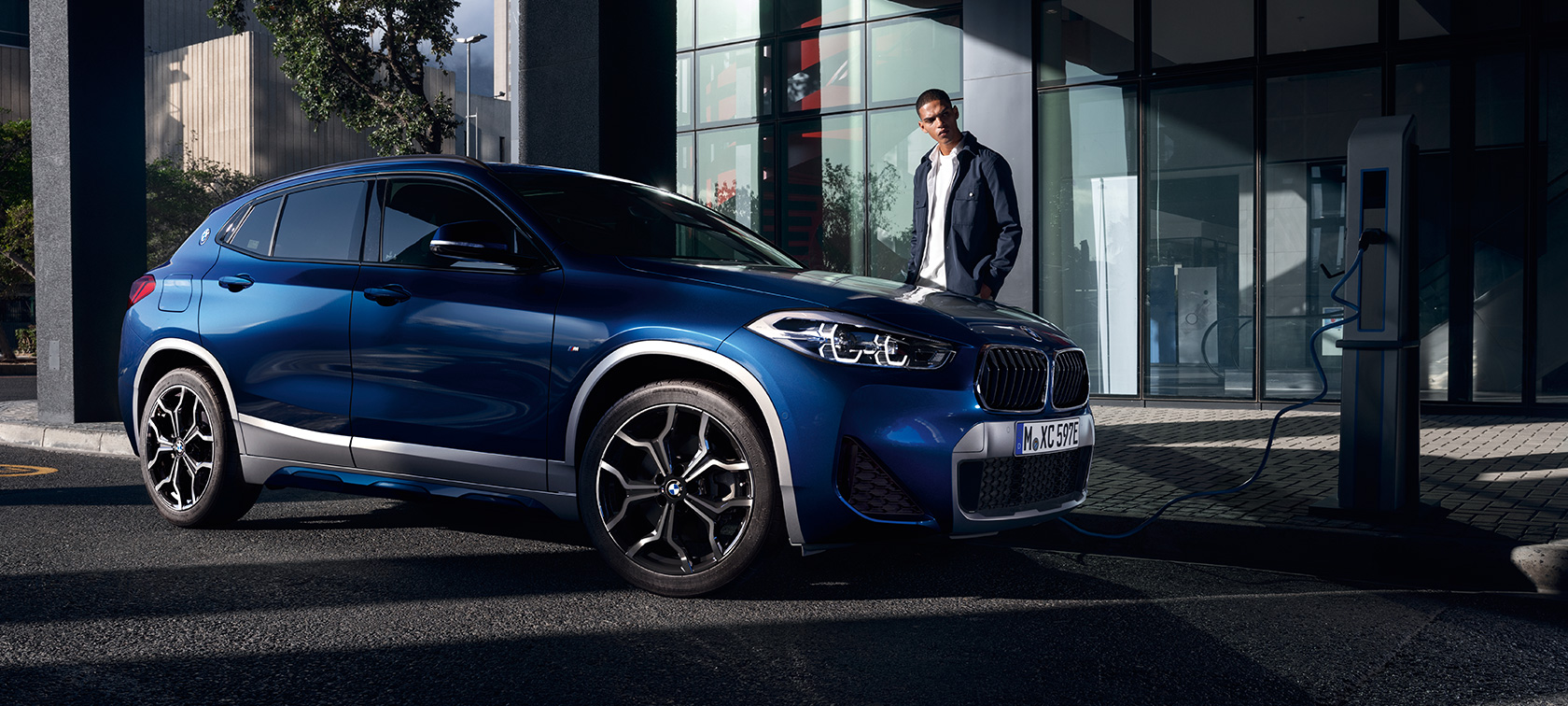 Plug-in Hybride BMW X2 xDrive25e F39 driekwart zijaanzicht bij laadstation Plug-in Hybride BMW X2 xDrive25e F39 driekwart zijaanzicht bij laadstation