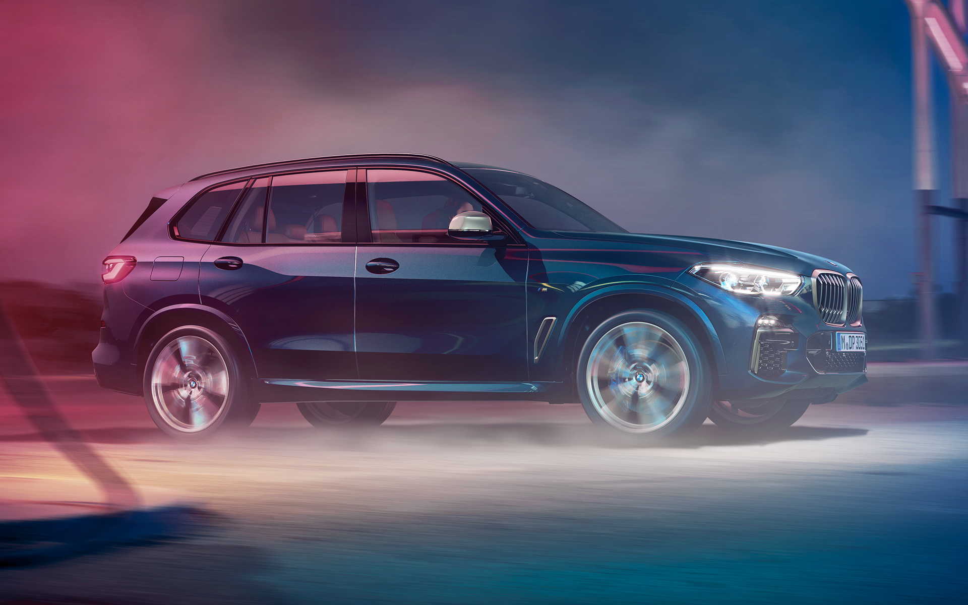 BMW X5 M50d rijdend Rijdende BMW X5 M50d met op de achtergrond een nachtelijke skyline