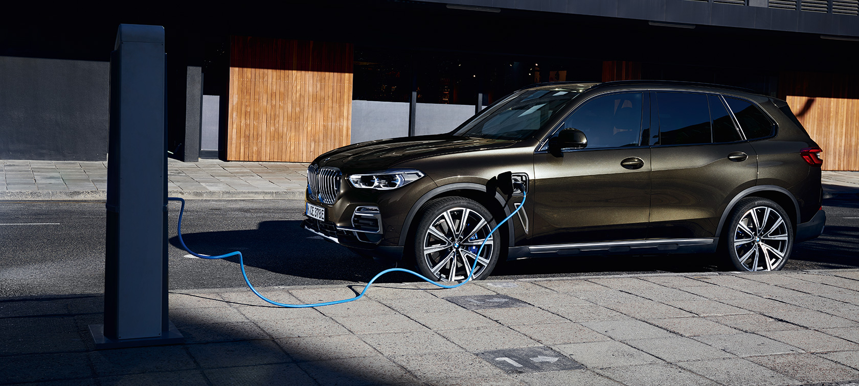 Plug-in Hybride BMW X5 SUV xDrive45e G05 driekwart zijaanzicht Plug-in Hybride BMW X5 SUV xDrive45e G05 driekwart zijaanzicht opladend