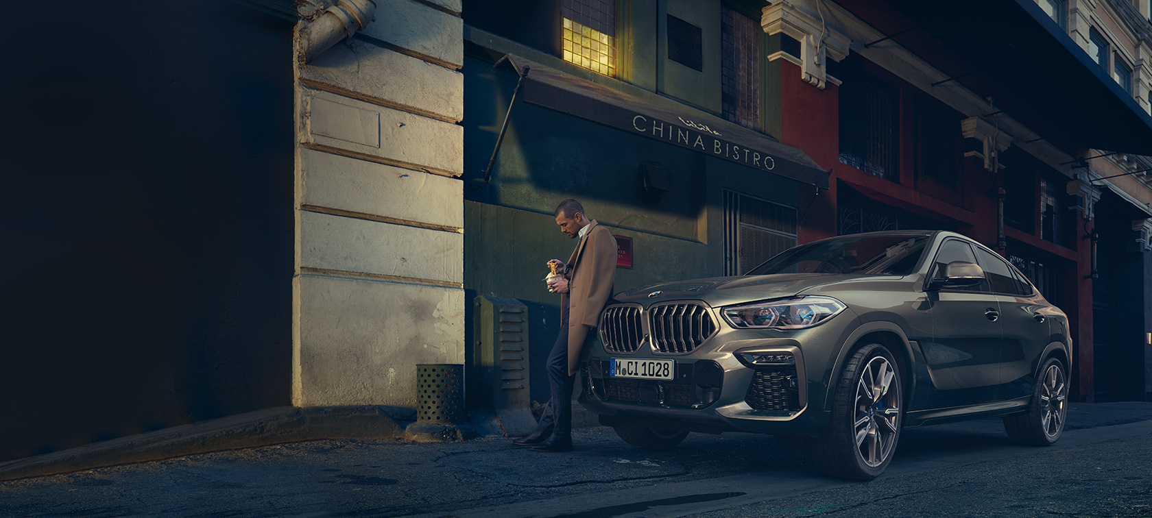 BMW X6 SUV driekwart achteraanzicht rijdend G06 BMW X6 SUV G06 Manhattan metallic driekwart achteraanzicht rijdend