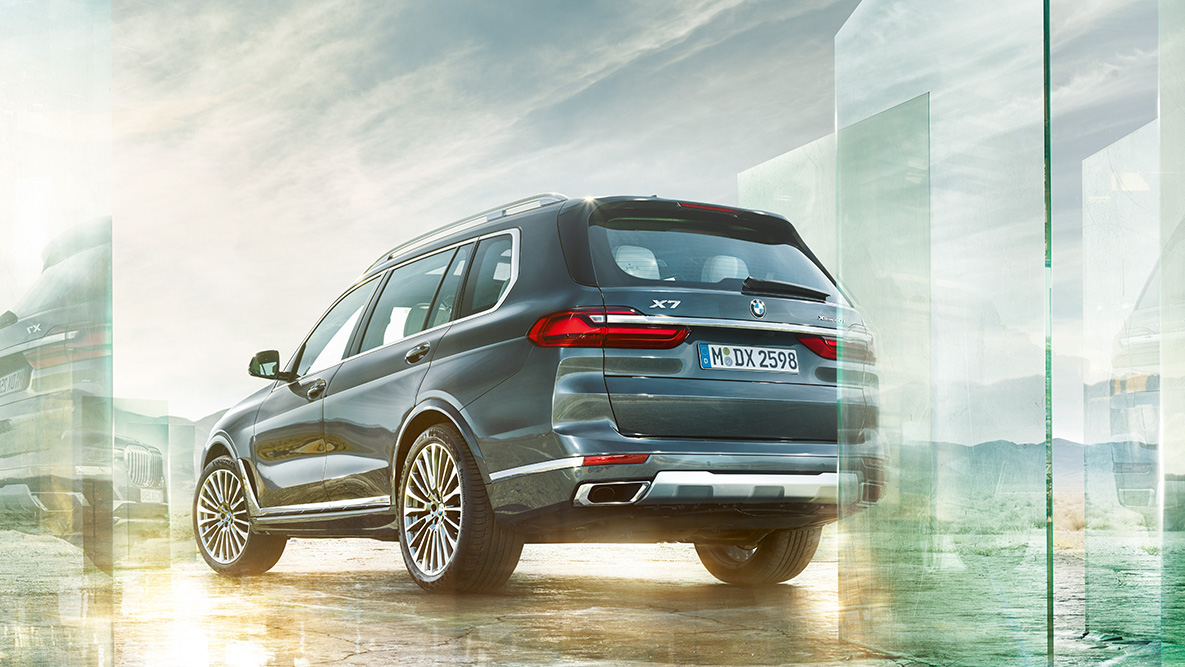 BMW X7 rijcomfort en rijdynamiek Driekwart achteraanzicht van een BMW X7 tegen een abstracte achtergrond