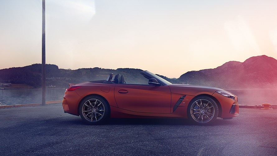 Oranje BMW Z4 First Edition stilstaand in de bocht Oranje BMW Z4 First Edition stilstaand in de bocht voor berglandschap