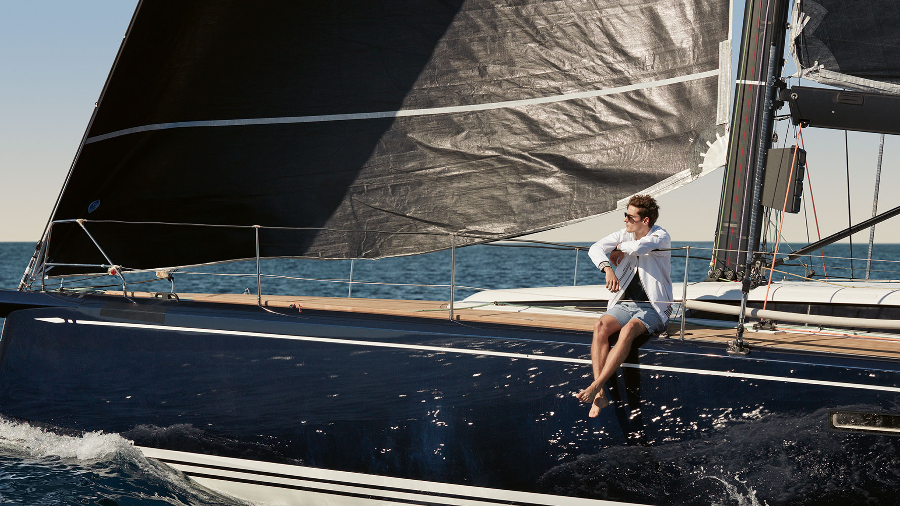 Een man op een zeiljacht draagt een BMW Yachtsport herenjack uit de BMW Yachtsport Collection Een man op een zeiljacht draagt een BMW Yachtsport herenjack uit de BMW Yachtsport Collection