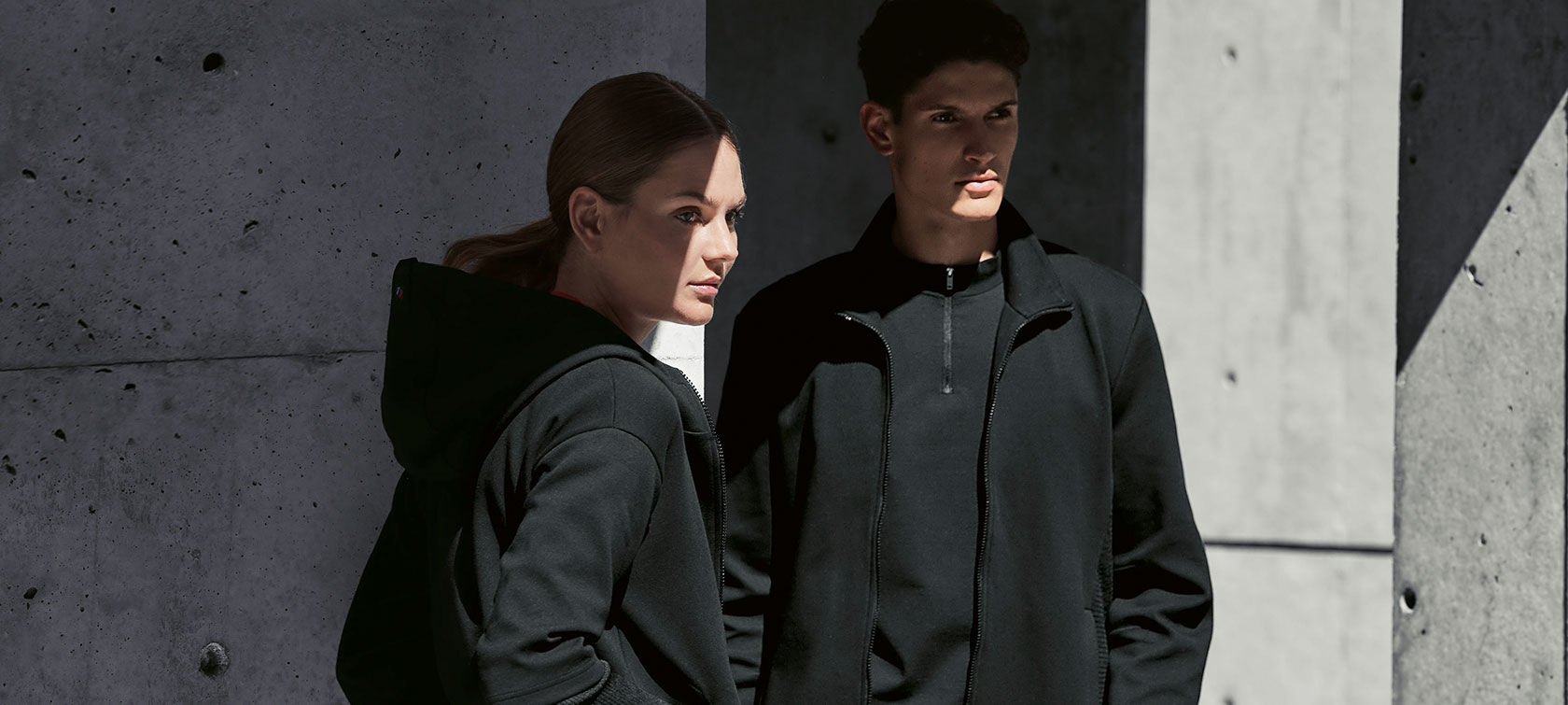 BMW M Sweatvest dames en BMW M Sweatvest heren. Een stel staat in de schaduw: de vrouw draagt het BMW M Sweatvest voor dames en de man het BMW M Sweatvest voor heren.