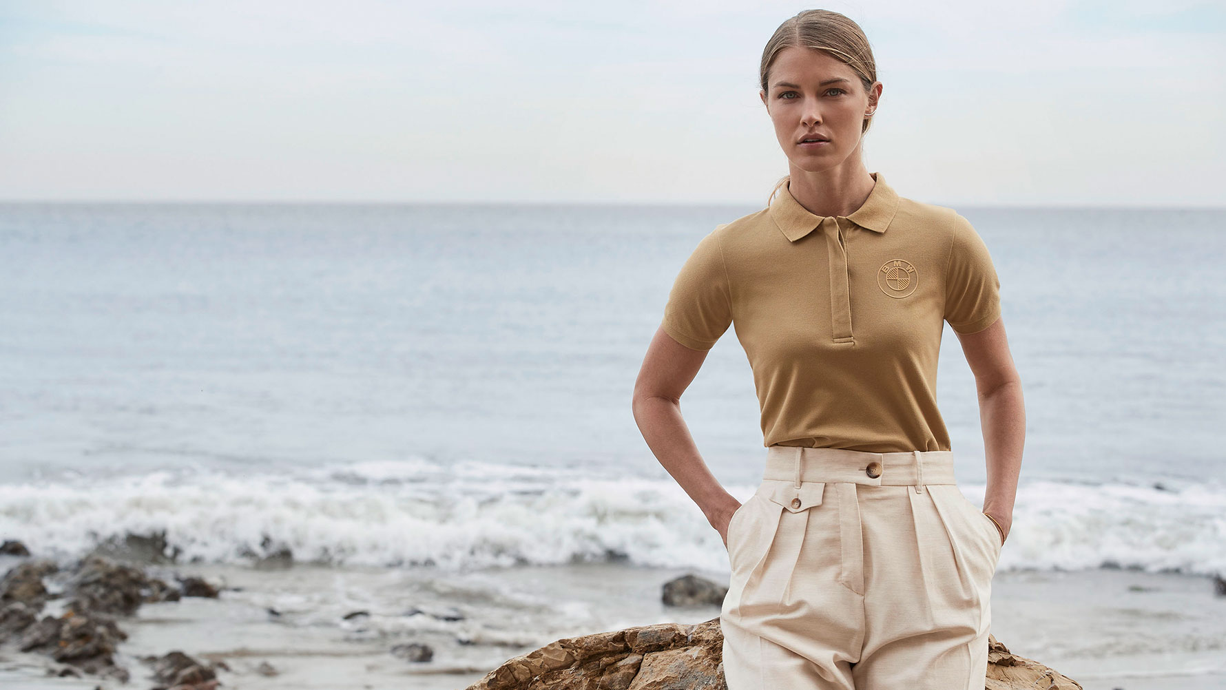 Een jonge vrouw aan het strand draagt het Poloshirt logo voor dames. Een jonge vrouw aan het strand draagt het Poloshirt logo voor dames.