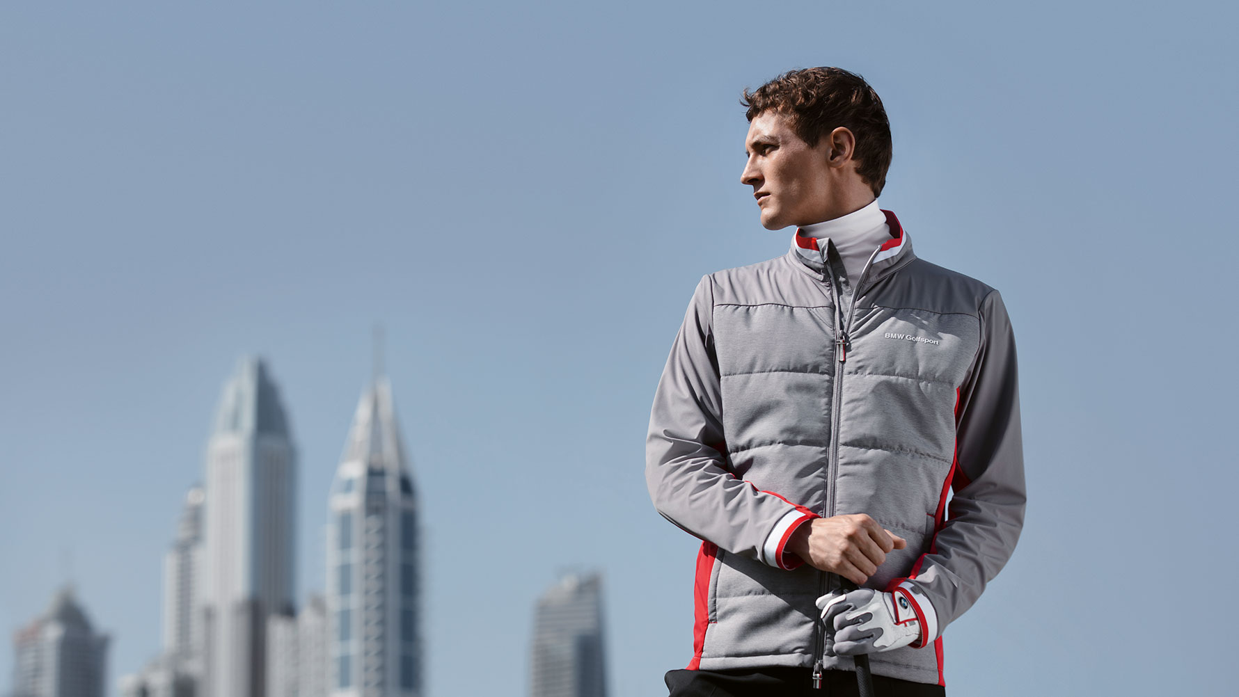 Een man draagt producten uit de BMW Golfsport Collection, met op de achtergrond de skyline van een stad. Een man draagt producten uit de BMW Golfsport Collection, met op de achtergrond de skyline van een stad.