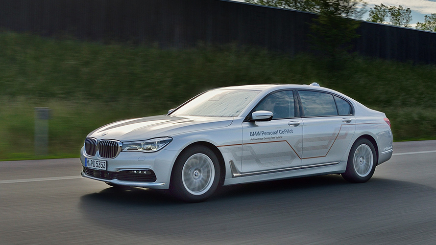 Grijze BMW 7 Serie Een grijze BMW 7 Serie rijdt op een weg met gras op de achtergrond