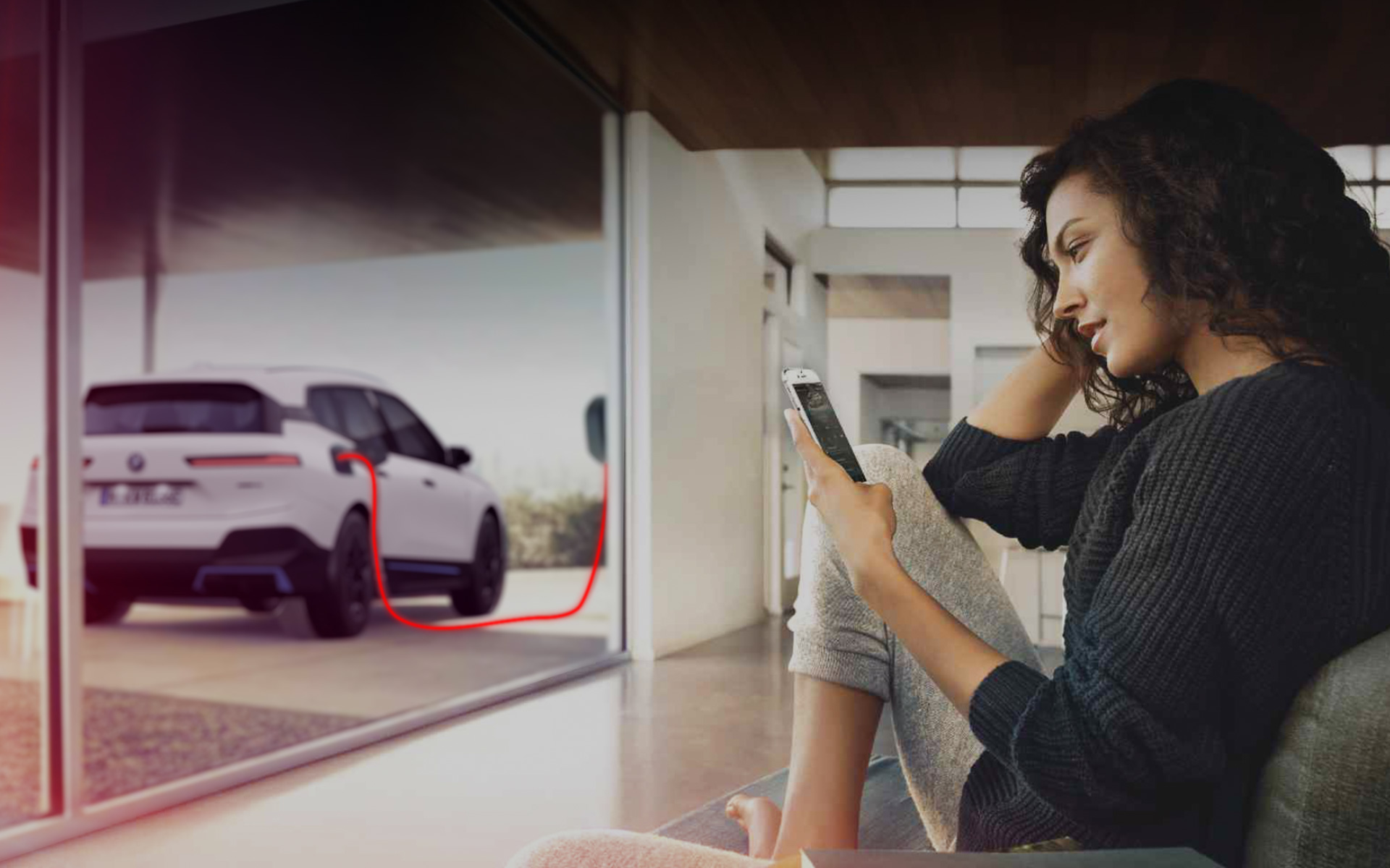 Thuis laden BMW iX i20 dame met smartphone 