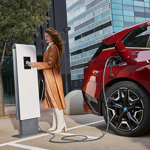 BMW iX i20 aan laadpaal vrouw met BMW Charging Card