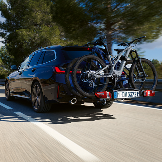 BMW 3 Serie Touring G21 PHEV 3/4 achteraanzicht met fietsen rijdend