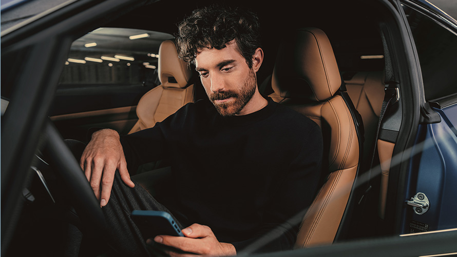 Man zit in BMW Man in BMW kijkt op smartphone