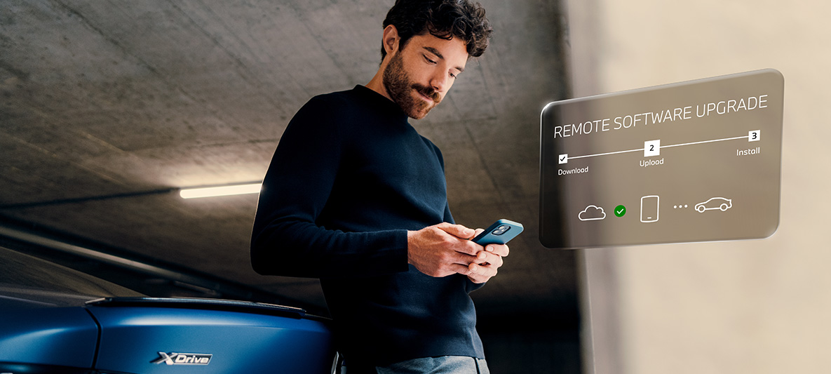 Man bij BMW kijkt op smartphone Remote Software Upgrade man bij BMW kijkt op smartphone