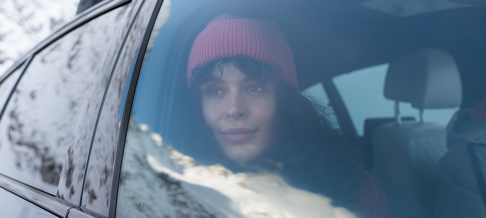 Vrouw kijkt naar buiten door het raam van een BMW BMW Accessoires voor herfst en winter vrouw kijkt naar buiten door raam van BMW