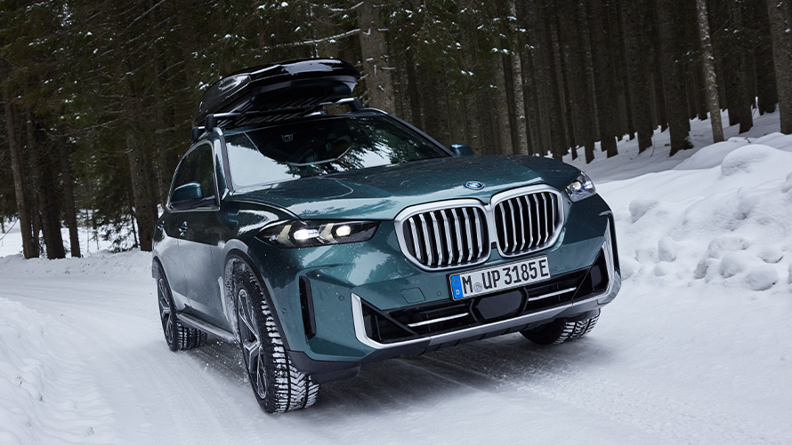BMW complete winterwielsets op een BMW X5 (G05 LCI) op besneeuwde weg in bos BMW complete winterwielsets op een BMW X5 (G05 LCI) op besneeuwde weg in bos