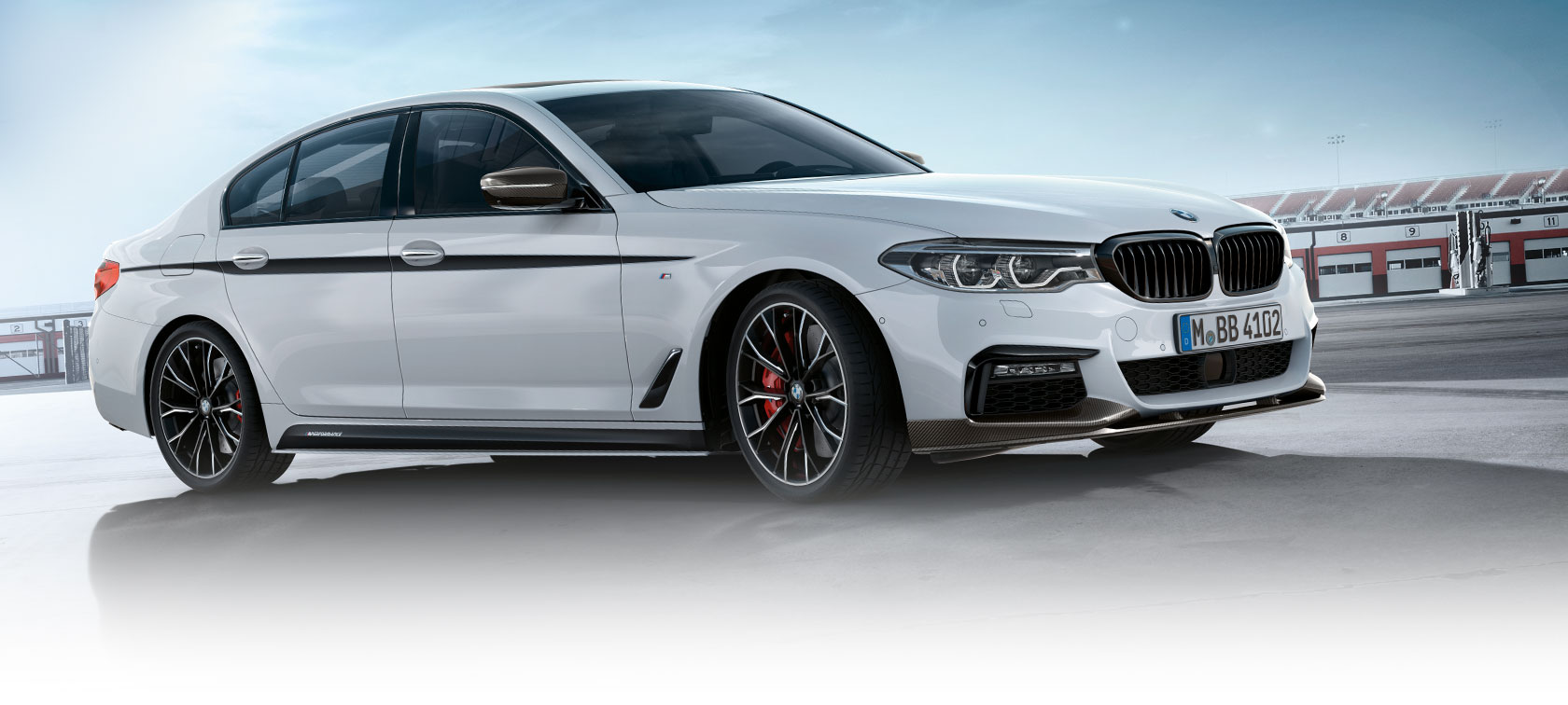 BMW 3 Serie Sedan, M Performance accessoires. Zijaanzicht van de BMW 3 Serie Sedan op parkeerplaats bij blauwe lucht.