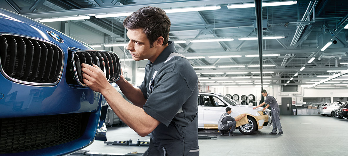 BMW herstelwerkzaamheden We zien een monteur die een BMW repareert