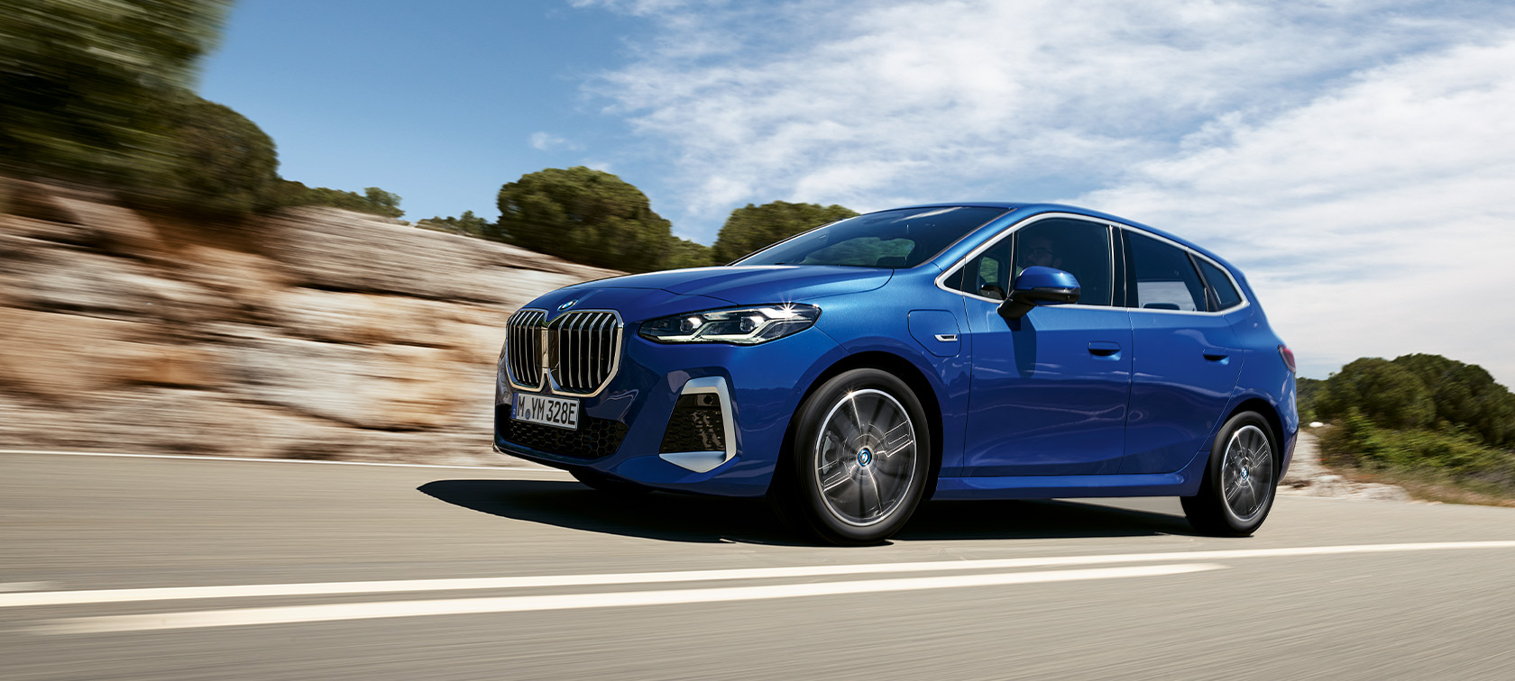 BMW 2 Serie Active Tourer 230e Plug-in Hybride U06 M Portimao Blau metallic driekwart vooraanzicht aan laadpaal