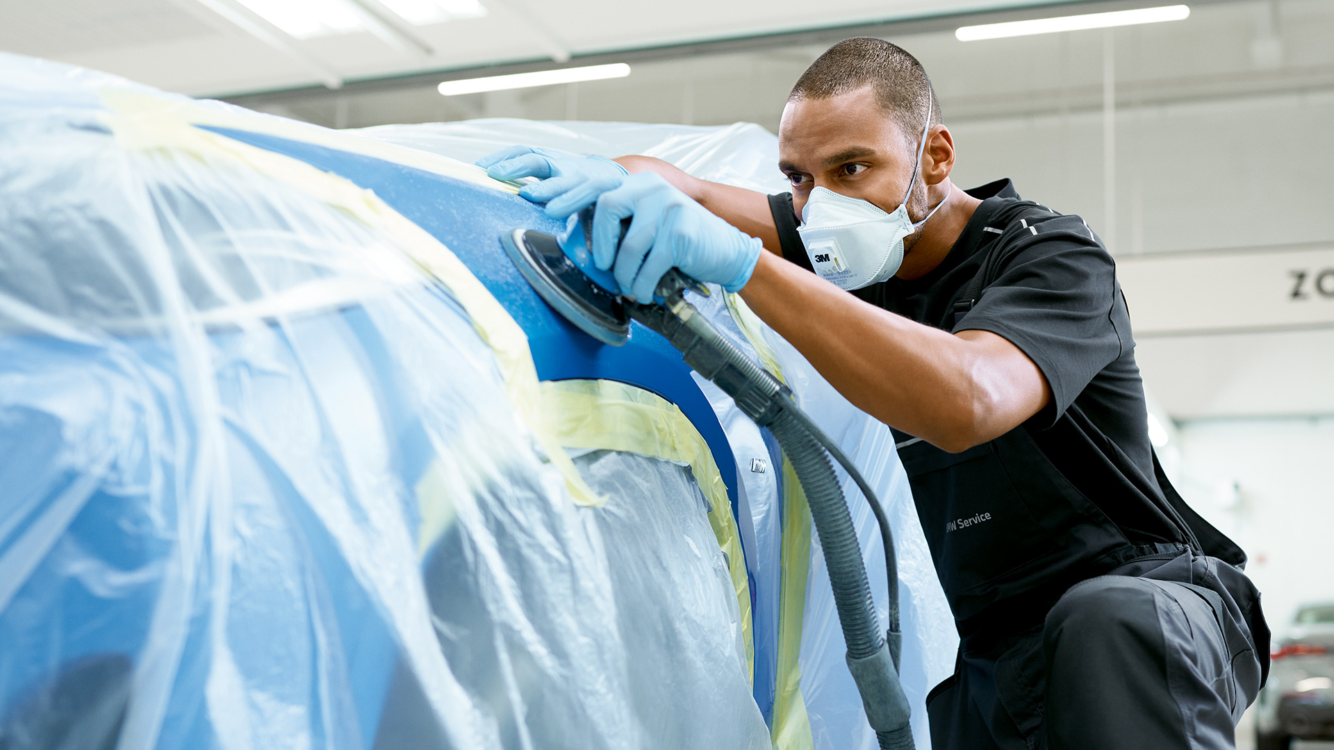 Man polijst bestickerde voorste wielkuip van BMW met machine